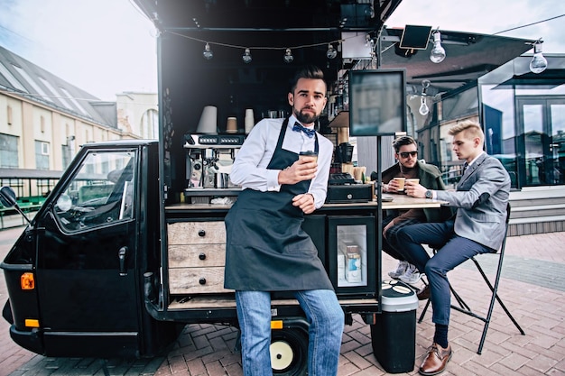 Ein hübscher gepflegter Barista macht eine Kaffeepause in der Nähe seines kleinen Coffeeshops.