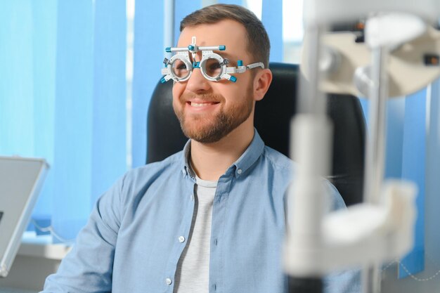 Ein hübscher junger Mann überprüft das Sehvermögen in einer modernen Augenklinik Patient in einer Augenklinik