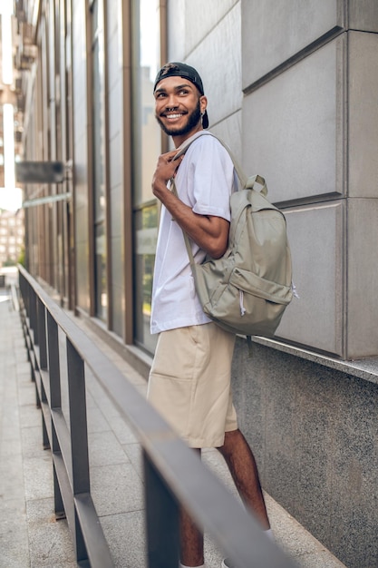 Foto ein hübscher lächelnder mann mit einem rucksack in der stadtstraße