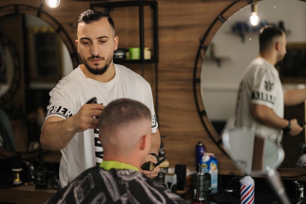 Ein hübscher Mann beim Friseur sitzt auf einem Stuhl und lässt sich beim Friseur die Haare schneiden