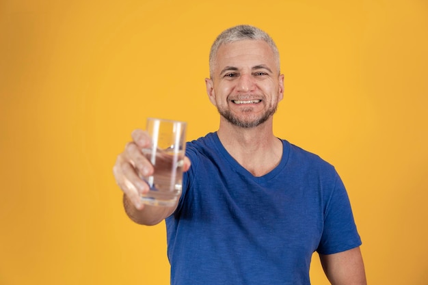 Ein hübscher reifer Mann, der ein Glas Wasser hält Trinkwasser des älteren Mannes