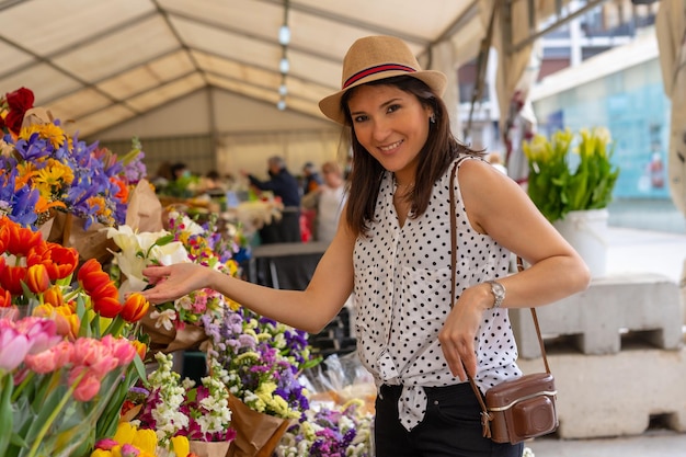 Ein hübscher Tourist mit einer Fotokamera, der einen Blumenmarkt besucht und Frühlings- oder Sommerferien genießt