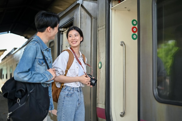 Ein hübsches junges asiatisches Paar mit Rucksäcken steigt gemeinsam in den Zug ein und reist