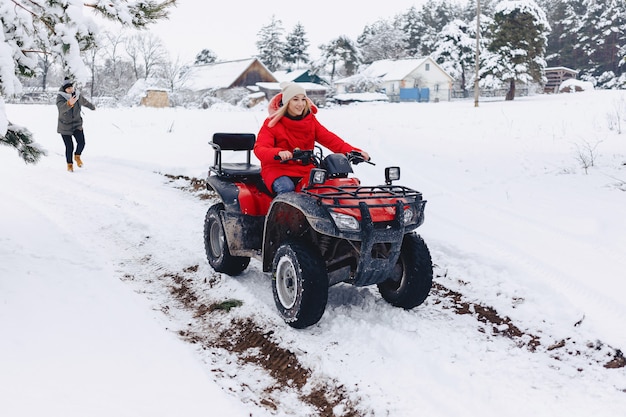 Ein hübsches Mädchen, das ein Quadrocycle in einem malerischen schneebedeckten Bereich reitet