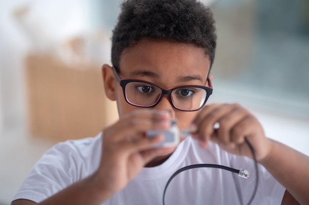 Ein hüfthohes Bild eines Jungen mit einem USB-Kabel in den Händen