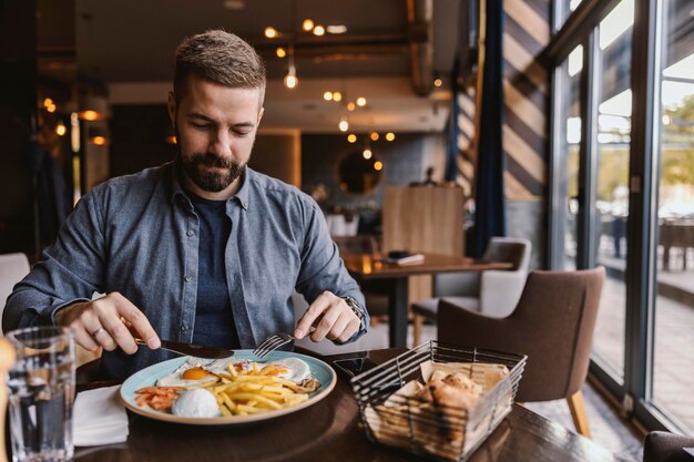 Ein hungriger Mann isst im Restaurant Eier zum Frühstück