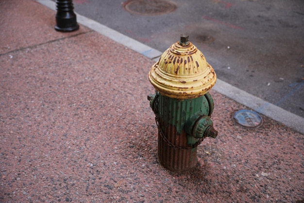 Ein Hydrant auf dem Bürgersteig ist grün und gelb.