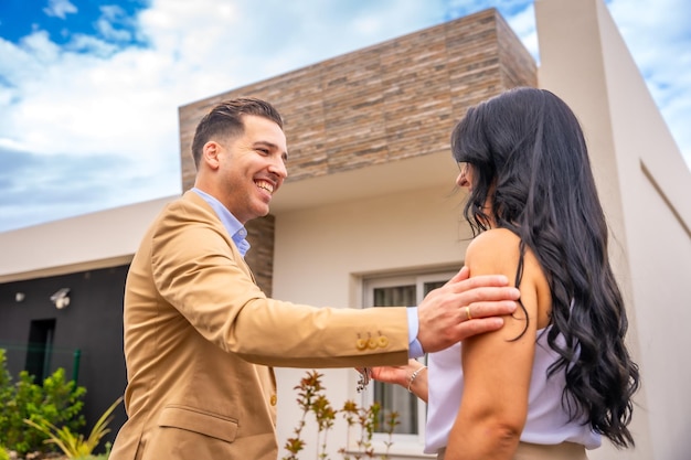 Ein Immobilienagent beglückwünscht einer Frau die Schlüssel zu ihrem neuen Haus in der Hand