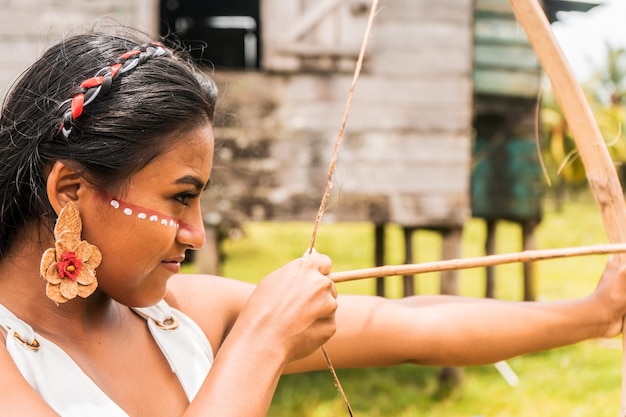 Ein indigenes Teenager-Mädchen mit bemaltem Gesicht, das Pfeile mit einem Holzbogen schießt, in einer nordkaribischen Gemeinde in Nicaragua