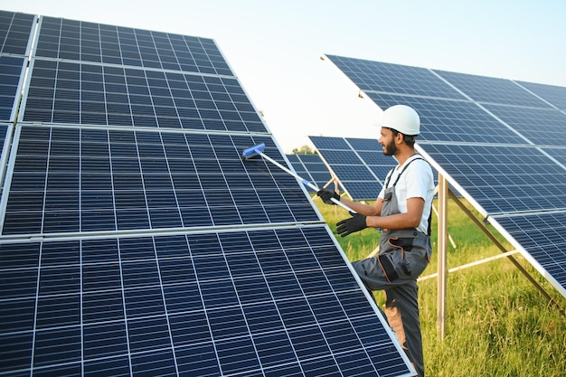 Ein indischer Mann in Uniform arbeitet in der Nähe eines Solarpanels