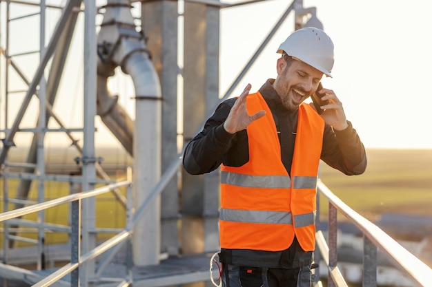 Ein Industriearbeiter steht auf der hohen Metallkonstruktion und telefoniert mit dem Manager