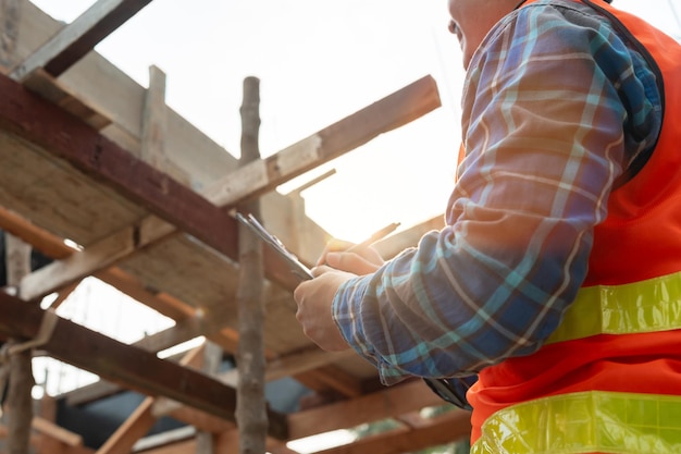 Ein Inspektor oder Ingenieur inspiziert den Bau und die Qualitätssicherung eines neuen Hauses anhand einer Checkliste. Ingenieure, Architekten oder Bauunternehmer arbeiten am Bau des Hauses, bevor sie es dem Hausbesitzer übergeben