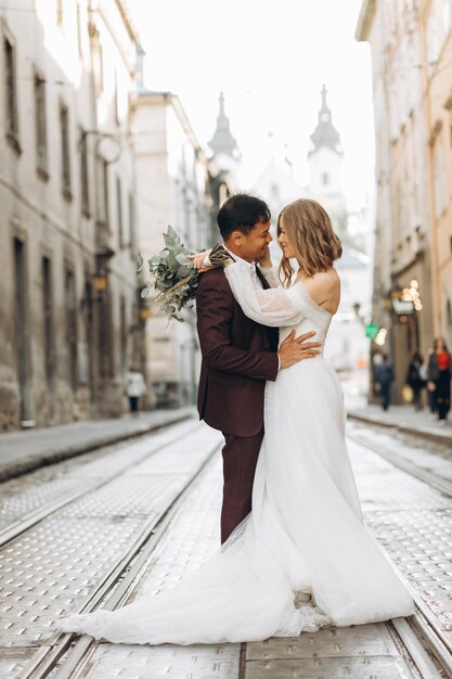 Ein internationales Hochzeitspaar, eine europäische Braut und ein asiatischer Bräutigam spazieren gemeinsam durch die Stadt