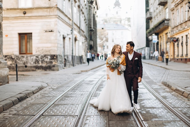 Ein internationales Hochzeitspaar, eine europäische Braut und ein asiatischer Bräutigam spazieren gemeinsam durch die Stadt