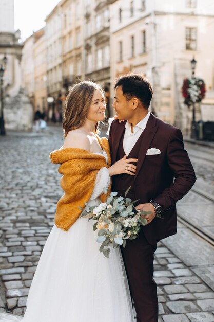 Ein internationales Hochzeitspaar, eine europäische Braut und ein asiatischer Bräutigam spazieren gemeinsam durch die Stadt