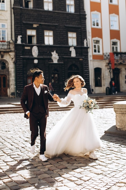 Ein internationales Hochzeitspaar, eine europäische Braut und ein asiatischer Bräutigam spazieren gemeinsam durch die Stadt