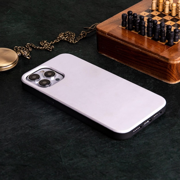 Ein iPhone mit der Rückseite der Hülle auf der Rückseite liegt auf einem Tisch neben einem Schachbrett.