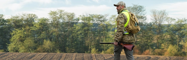 Ein Jäger mit Gewehr in der Hand in Jagdkleidung im herbstlichen Wald auf der Suche nach einer Trophäe Ein Mann steht mit Waffen und Jagdhunden auf der Jagd nach dem Wild