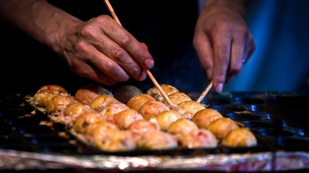 Foto ein japanischer verkäufer bereitet eine takoyaki auf heißer pfanne vor japan gebratene oktopuskugeln