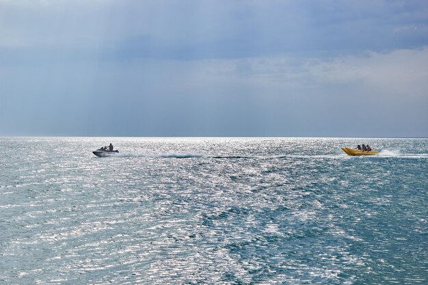 Ein Jetski zieht ein Bananenboot mit Menschen Bananenbootfahrt Ruhiges blaues Meer Sommerurlaub am Meer