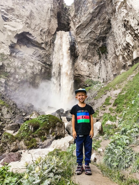 Ein Junge am Wasserfall Sultansu, umgeben von den Bergen des Kaukasus in der Nähe von Elbrus Jilysu Russland
