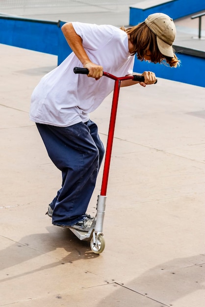 Ein Junge auf einem Roller und in einem Skatepark macht unglaubliche Sprünge und Tricks Extremes Springen auf einem Roller Das Konzept eines gesunden Lebensstils und sportlicher Freizeit