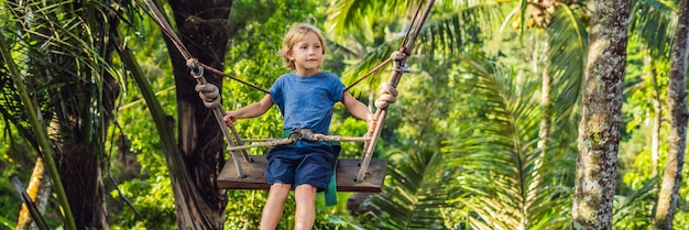 Ein Junge auf einer Schaukel über dem Dschungel, Bali BANNER, Langformat