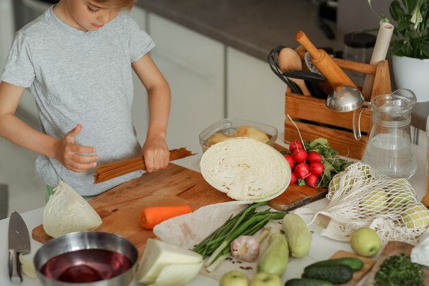 Ein Junge, der mit Gemüse in der Küche kocht