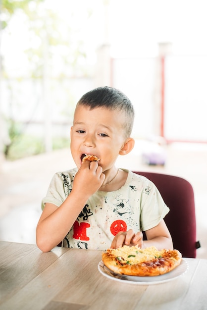 Ein Junge, ein Kind auf der Straße isst eine Minipizza sehr appetitlich