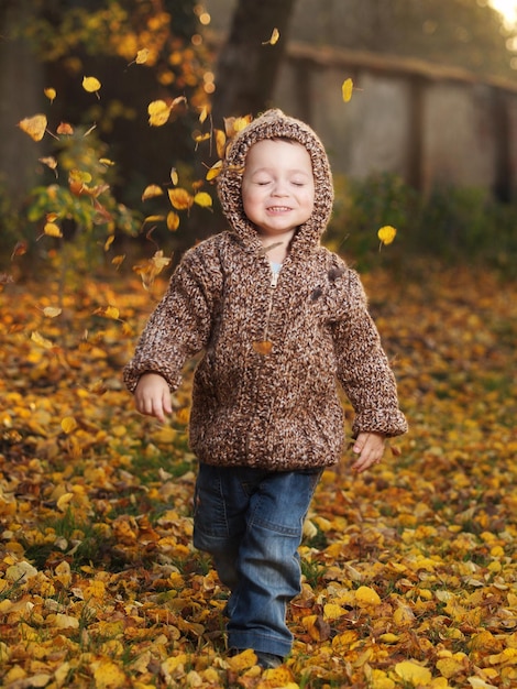 Ein Junge geht im Herbst auf Blättern