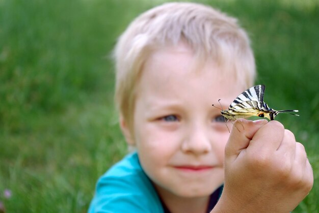 Foto ein junge hält einen schmetterling, der schmetterling genannt wird.