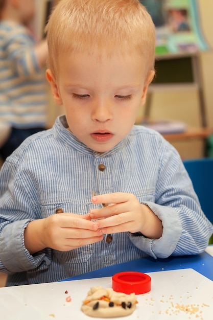 Ein Junge im Kindergarten bastelt aus Plastilinex9