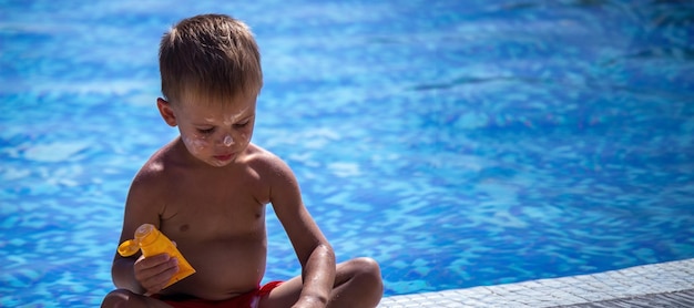 Ein Junge im Pool beschmiert sich mit Sonnencreme. Selektiver Fokus Urlaub