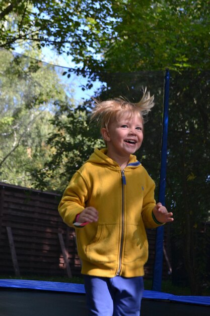 Ein Junge in einer gelben Jacke läuft auf einem Trampolin.