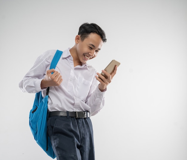 Ein Junge in einer Junior-High-School-Uniform, der mit einer aufgeregten Geste mit einem Hintern auf ein Handy schaut.