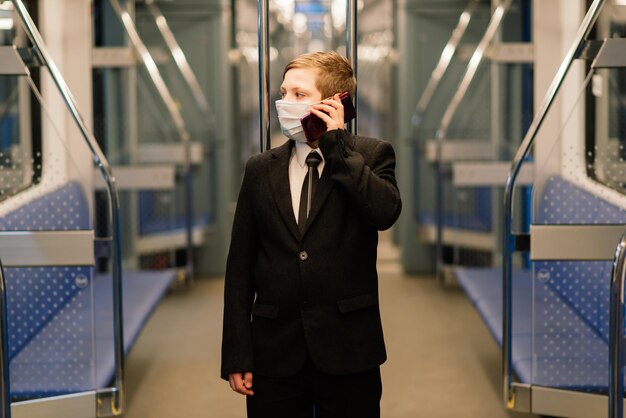 Ein Junge in einer medizinischen Maske ist traurig am Zugfenster, ein Kind reist allein.
