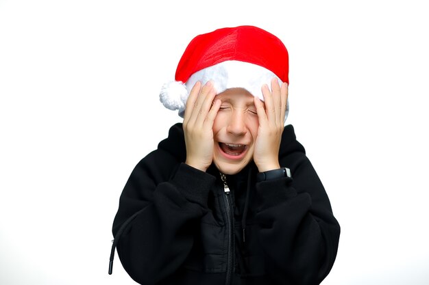 Ein Junge in einer roten Weihnachtsmütze hält sich fest und hält sich vor Angst mit den Händen die Augen zu