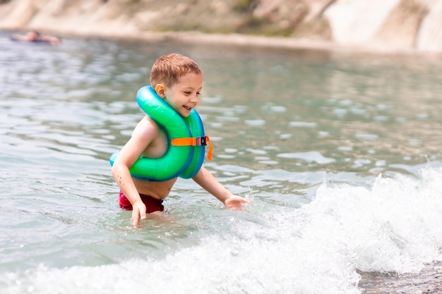 Ein Junge in einer Schwimmweste steht im Meer