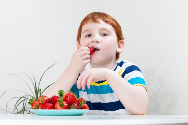 Ein Junge isst reife Erdbeeren