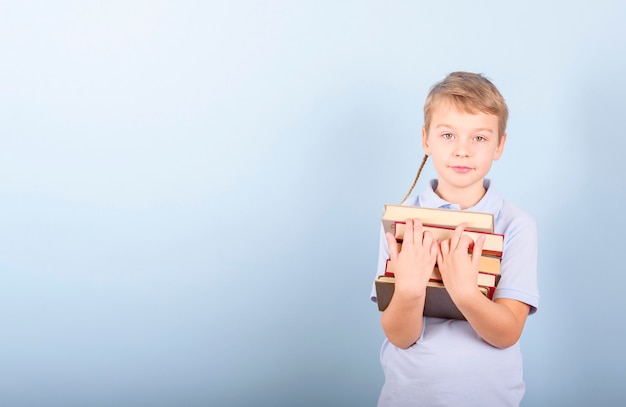 Ein Junge liest ein Buch auf blauem Hintergrund, ein Konzept von Bildung, Schule und Liebe zum Lesen