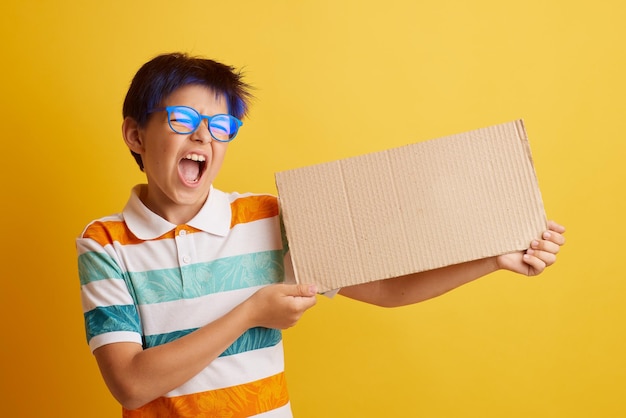 Ein Junge mit Brille auf gelbem Hintergrund mit unterschiedlichen Emotionen hält ein Pappbanner mit leerem Platz für Text