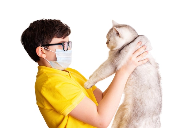 Ein Junge mit Brille und medizinischer Maske hält seine weiße Katze