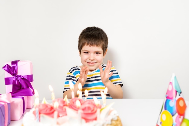 Ein Junge mit einem Kuchen an seinem Geburtstag klatscht in die Hände