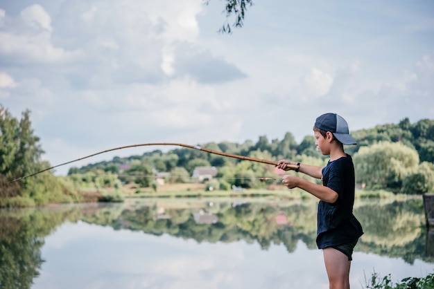 Ein Junge mit einer Angelrute und Angeln im See, Sommeraktivitäten und Hobbys für Kinder