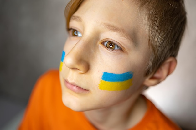 Ein Junge mit einer bemalten Flagge der Ukraine hob den Kopf nach oben