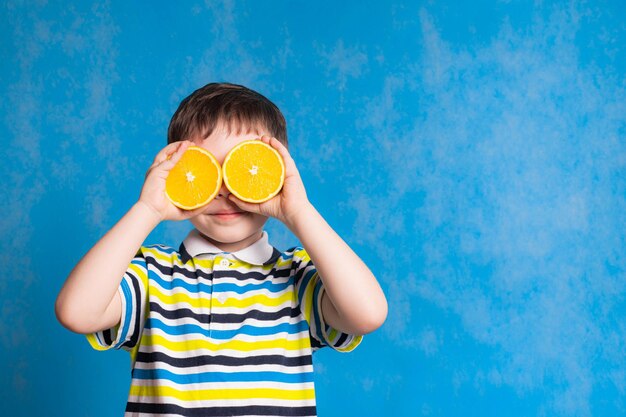 Ein Junge mit einer Orange auf blauem Hintergrund Ein Artikel über Babynahrung Vitamine für Babys Kopieren Sie Platz