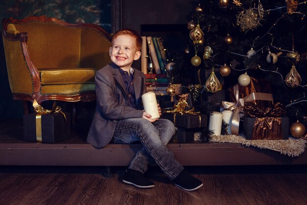 Ein Junge mit roten Haaren und Sommersprossen neben Weihnachtsbaum