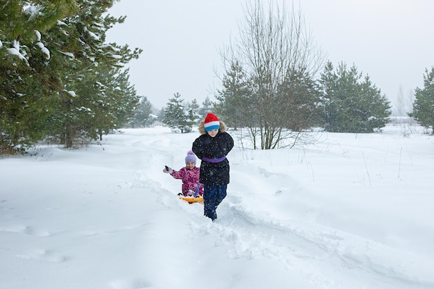 Ein Junge rollt ein kleines Mädchen im Schnee auf einer Eisbahn