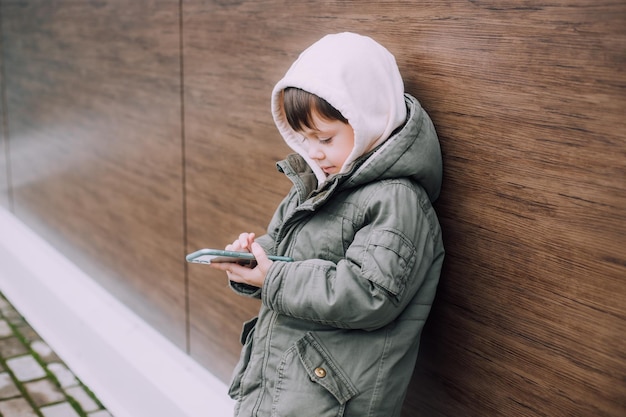 Ein Junge schaut auf sein Telefon in der Stadt des Lebensstils Moderne Technologien Moderne Kinder Ein Kind und ein Telefon