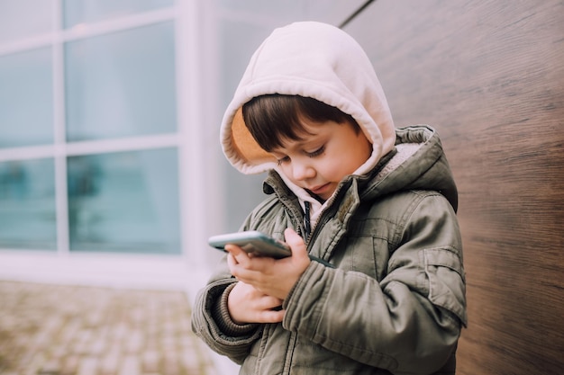 Ein Junge schaut auf sein Telefon in der Stadt des Lebensstils Moderne Technologien Moderne Kinder Ein Kind und ein Telefon